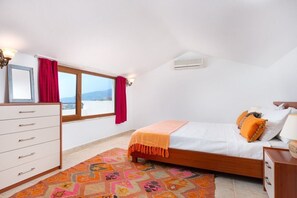 Quarto com cama, penteadeira, janela com vista e ventoinha no teto.