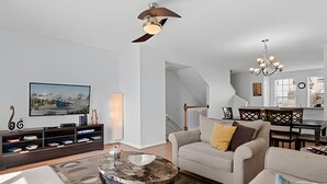 Een moderne woonkamer met een bank, een salontafel, een televisie en een trap naar een eethoek.