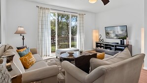 Een woonkamer met een bank, een salontafel, een televisie en een plafondventilator.