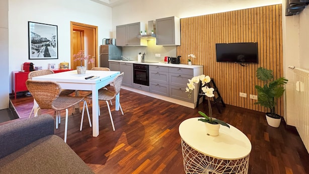 Een moderne keuken met grijze kastjes, een ingebouwde oven en een houten wandpaneel.