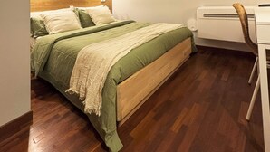 Een slaapkamer met een bed, bureau en raam.