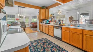 A spacious kitchen with wooden cabinets, a dishwasher, and a large island. There is a dining area with a table and chairs, and a view of the outdoors. - 1925 5-bedroom Historical home Downtown Sebring 
5 miles to Racetrack (Sebring)