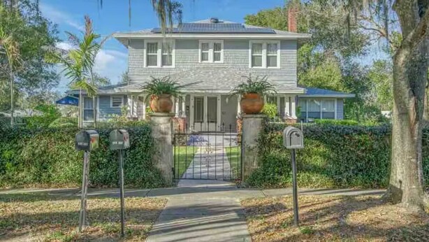 A two-story house with a front porch, a gated driveway, and mailbox posts. - 1925 5-bedroom Historical home Downtown Sebring 
5 miles to Racetrack (Sebring)