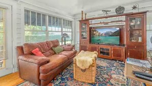 A living room with a leather sofa, a television, and a cabinet. - 1925 5-bedroom Historical home Downtown Sebring 
5 miles to Racetrack (Sebring)