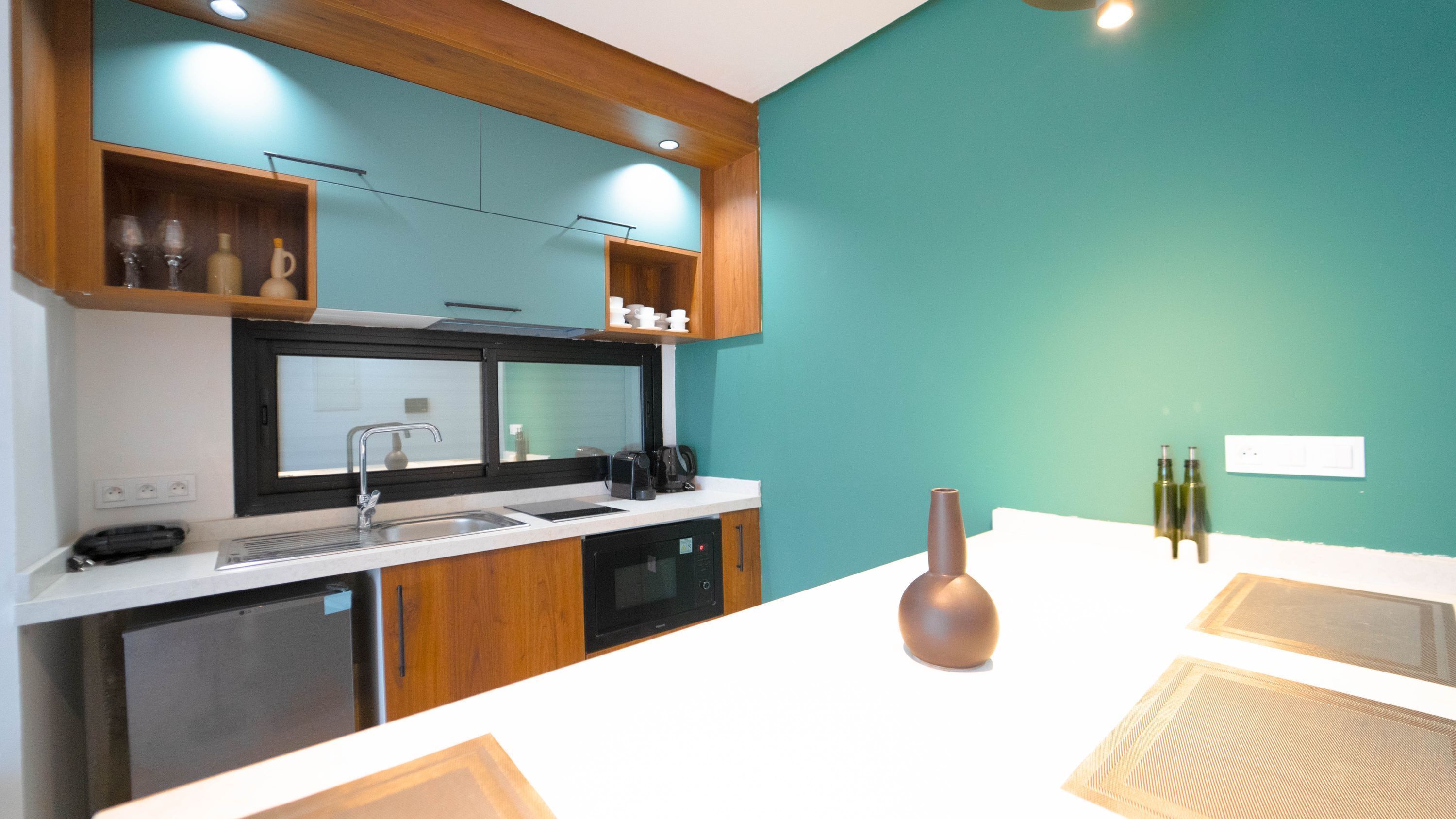 A modern kitchen with a white countertop, stainless steel appliances, and teal walls.