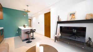 Ein modernes Wohnzimmer mit Kamin, einer Küchenzeile mit Barhocker und einer Wand in Türkis.
