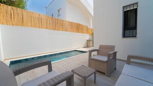 Un espace piscine aménagé avec des meubles en osier et une clôture en bois.