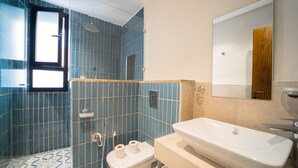 Une salle de bain équipée d’une douche, de toilettes, d’un lavabo et d’un miroir.