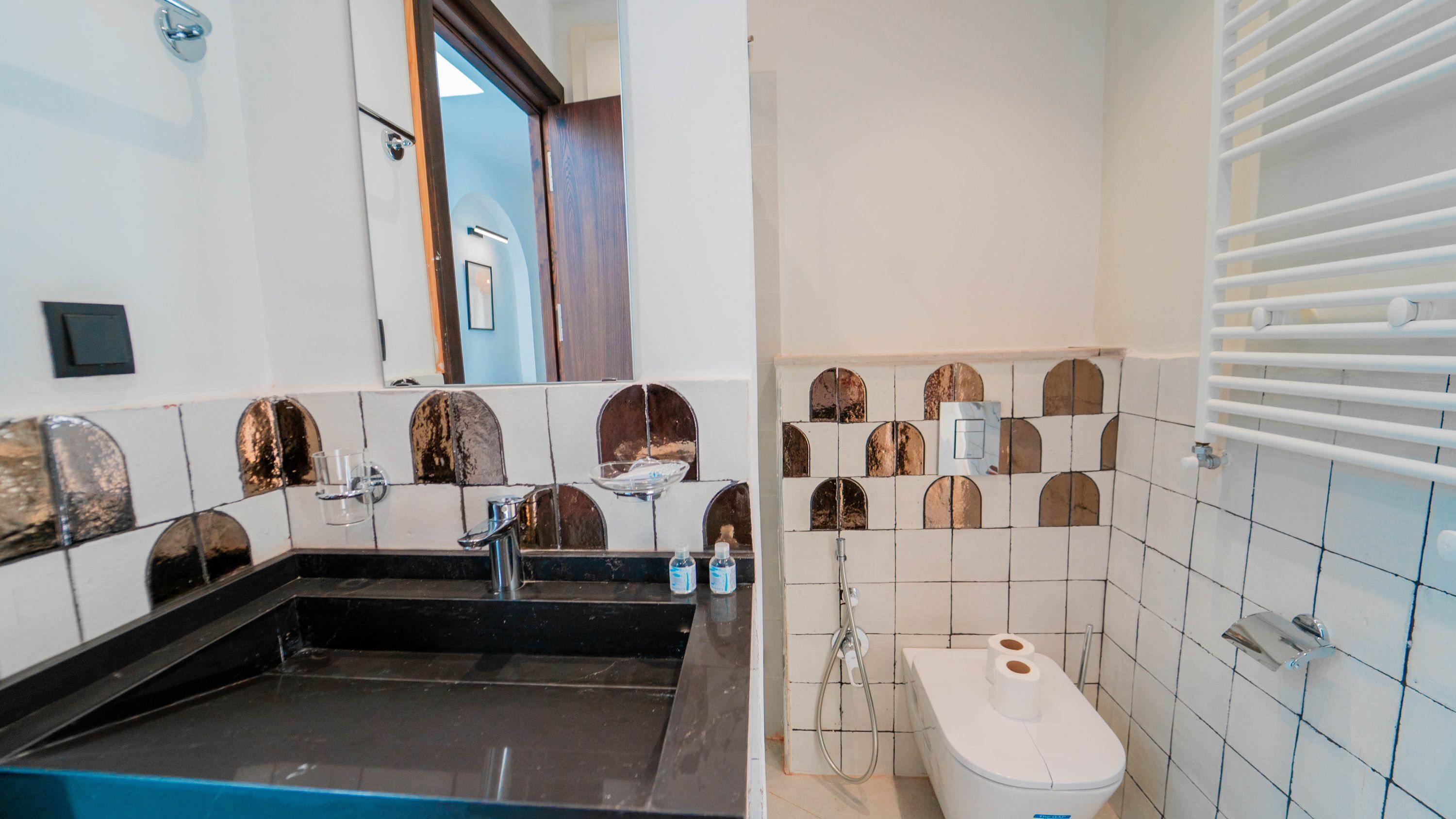 A bathroom with a black sink, a mirror, and a toilet with a white lid.