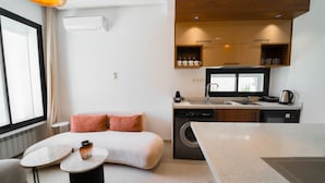 A compact hotel room with a bed, a small table, a washing machine, a kitchenette, and a window. - Aurora La Marsa RDC Modernit Charme (La Marsa)