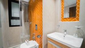 A modern bathroom with a glass shower enclosure, a white sink with a mirror, and orange patterned tiles. - Aurora La Marsa RDC Modernit Charme (La Marsa)