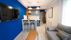 Una sala moderna con un sofá gris, una mesa de centro de madera y una pared azul destacada.