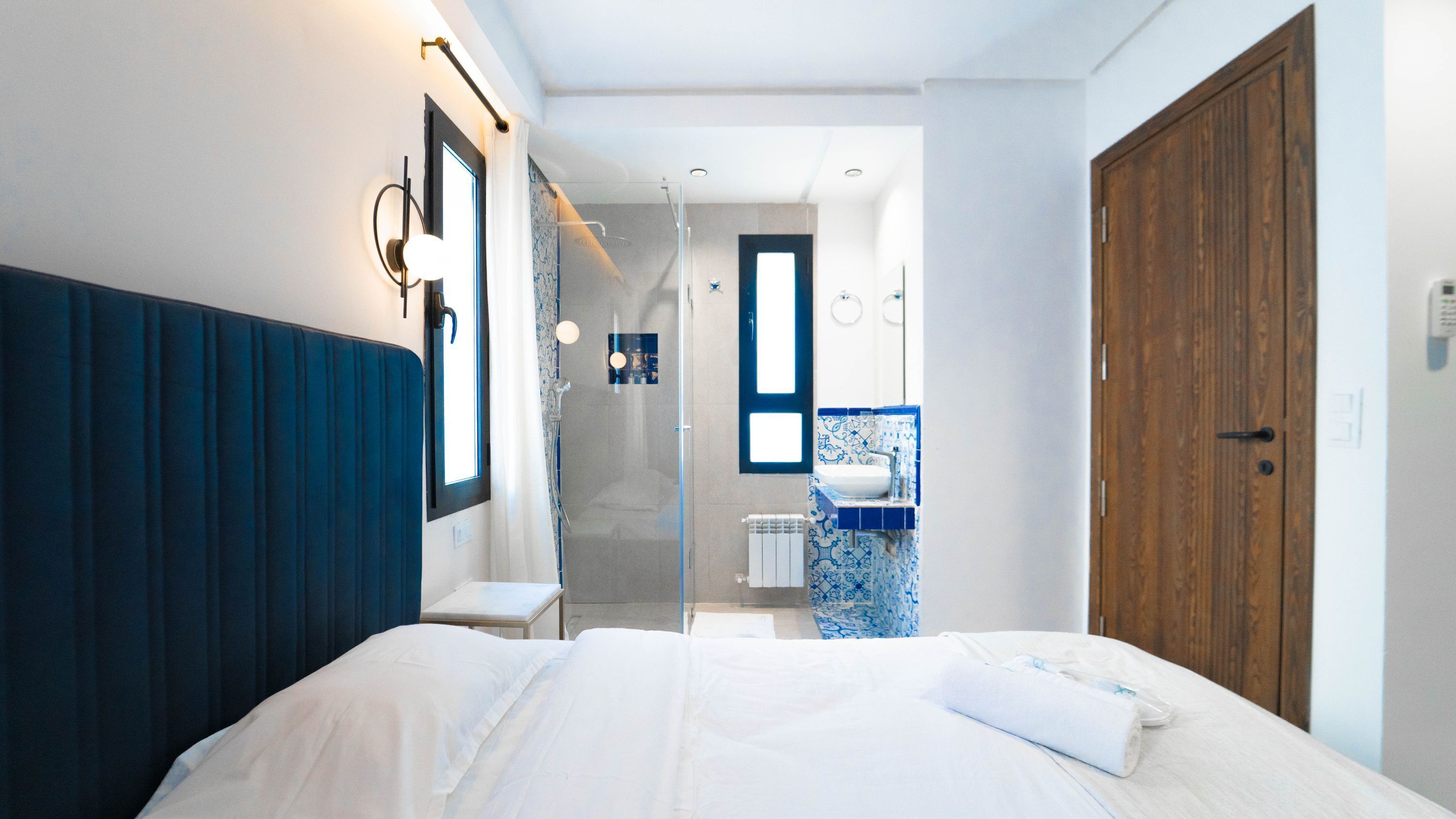 Une chambre moderne avec un grand lit, une porte en bois et une salle de bain équipée d’une douche et d’un lavabo.