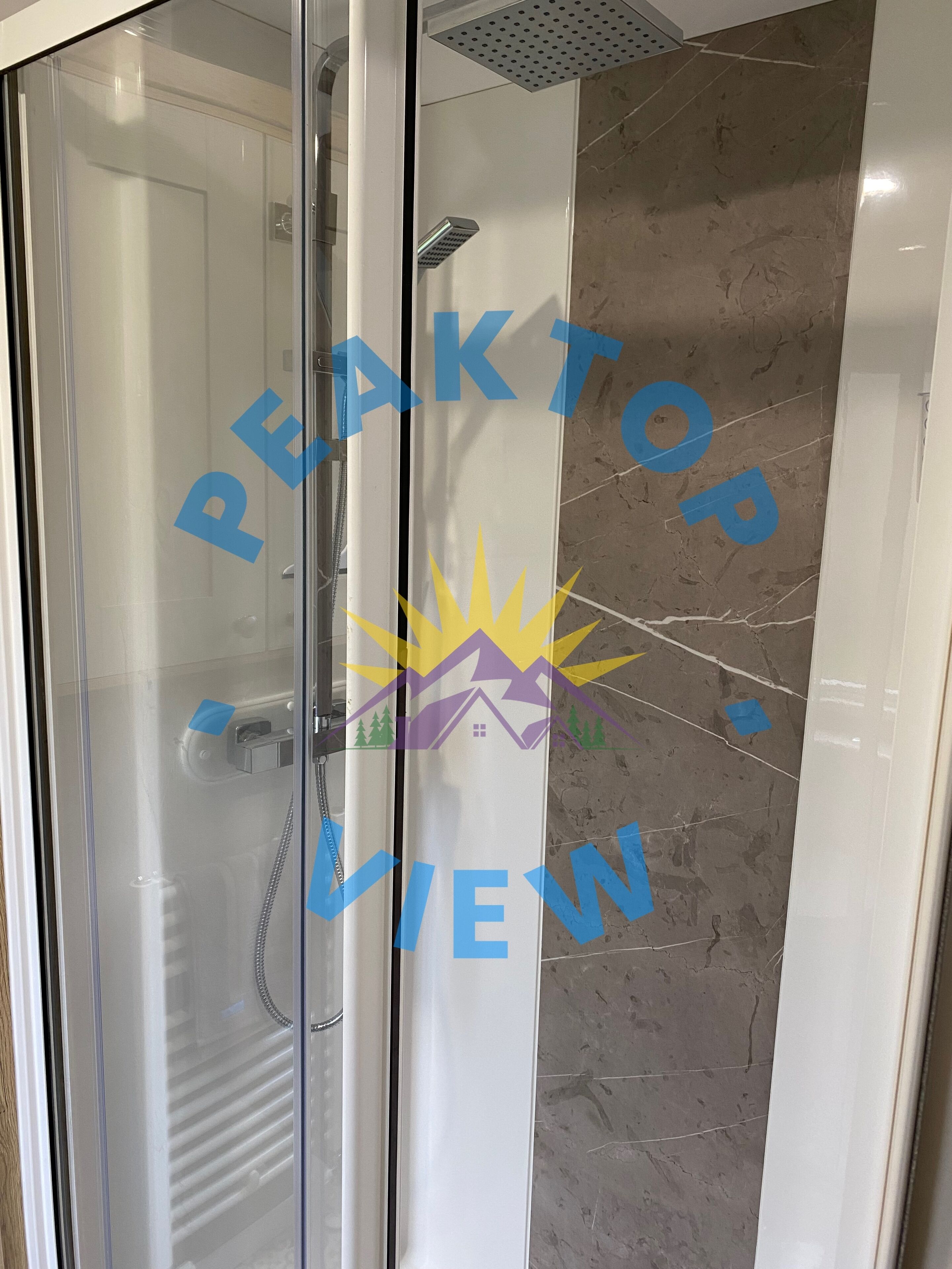 Cabina doccia in vetro con soffione a mano e rubinetto a parete.