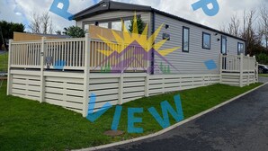 A mobile home with a fenced patio area, a small deck, and a sign indicating 'Tractor View'.