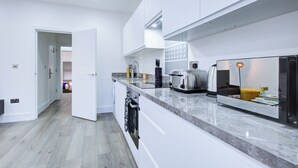 Eine moderne Küche mit weißen Schränken, einer Marmorarbeitsplatte, einem eingebauten Backofen und einem Toaster.