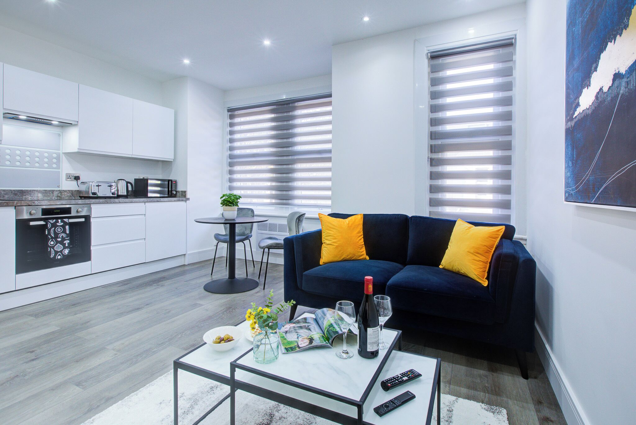 A modern living room with a sofa, a coffee table, and a dining area with a table and chairs.