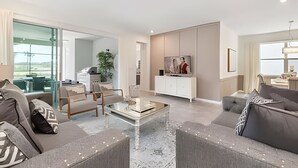 A modern living room with a glass partition, a dining area, and a kitchen. - Elegant 7BR Villa w/ Pool & Resort Access (Kissimmee)