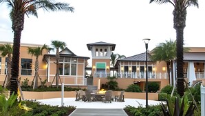 A hotel with a central courtyard, outdoor seating area, and palm trees. - Elegant 7BR Villa w/ Pool & Resort Access (Kissimmee)