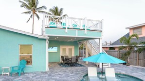Ein zweistöckiges Haus mit Pool, einem Balkon mit Stühlen und einem Essbereich.