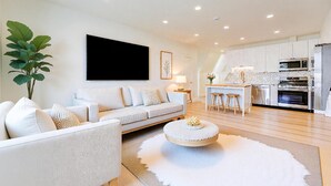 A modern living room with a sofa, a coffee table, and a TV. - Spacious 2BR Apartment, 10 min to Time Square! (Weehawken Township)