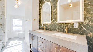 A modern bathroom with two sinks, marble backsplash, and a large mirror. - Spacious 2BR Apartment, 10 min to Time Square! (Weehawken Township)