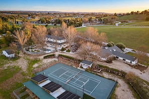 A residential area with multiple houses, a tennis court, and a fenced field.