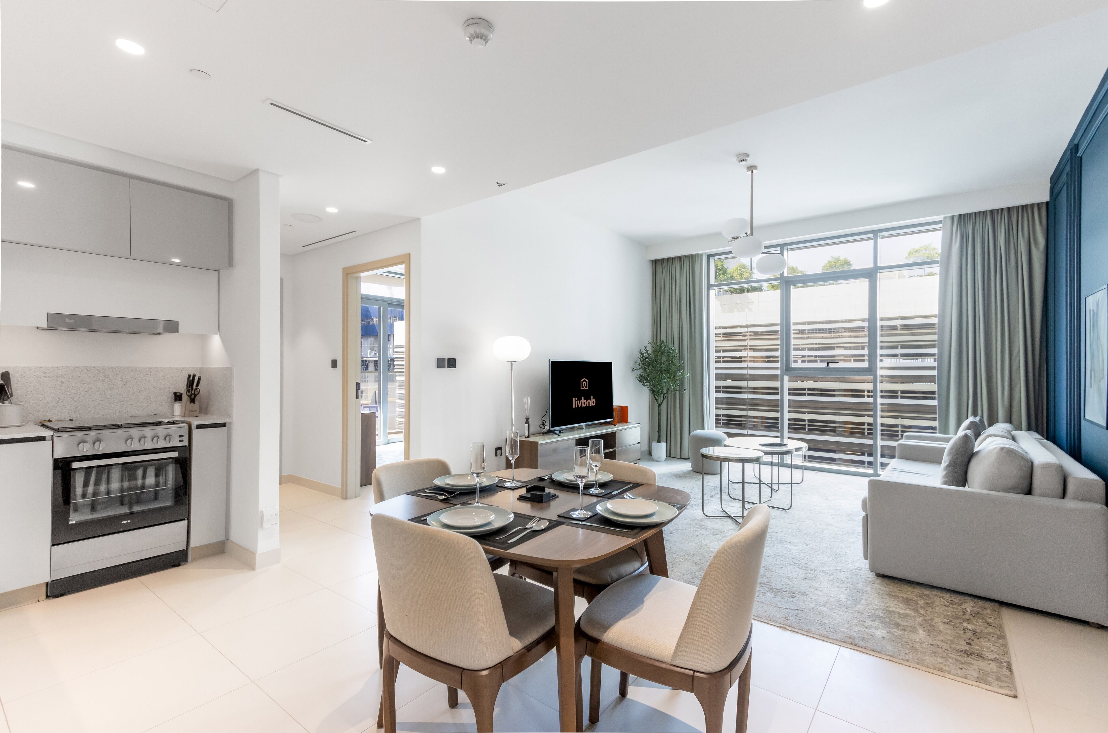 Un appartement moderne comprenant une cuisine, un coin repas et un salon. Il est équipé d’un téléviseur, d’une table à manger, de chaises et d’un canapé.