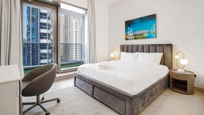 Et moderne hotelværelse med en stor seng, et skrivebord, en stol og udsigt over bybilledet gennem vinduet.