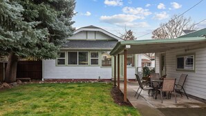 Une maison avec un patio couvert, une pelouse et un arbre.