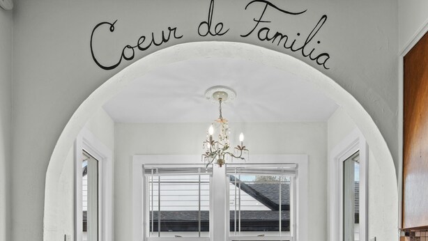 Un coin repas avec une table blanche, quatre chaises et un lustre.