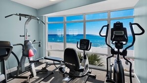 A gym with cardio machines and a rowing machine, overlooking a beach. - Emerald Isle 1406 (Panama City Beach)
