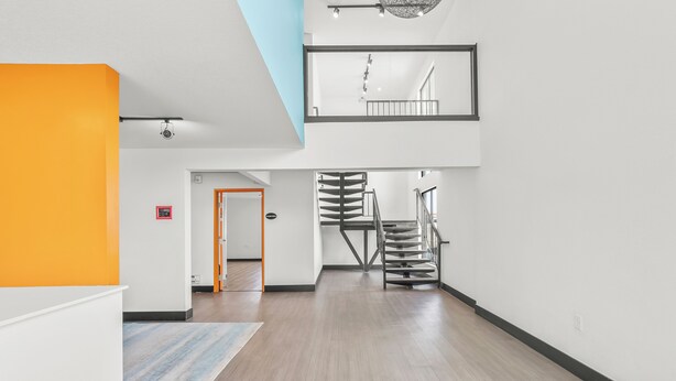A spacious hallway with a modern staircase, a visible fire alarm, and a ceiling light fixture. - Chic 1-bedroom Micro Studio Apartment (Cedar Falls)