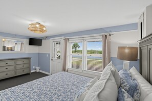Ein Schlafzimmer mit einem Bett, einem Schminktisch, einem Fernseher und einem Fenster mit Landschaftsblick.