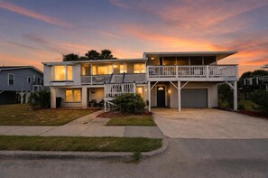 A two-story residential building with a balcony, a garage, and a well-maintained lawn.