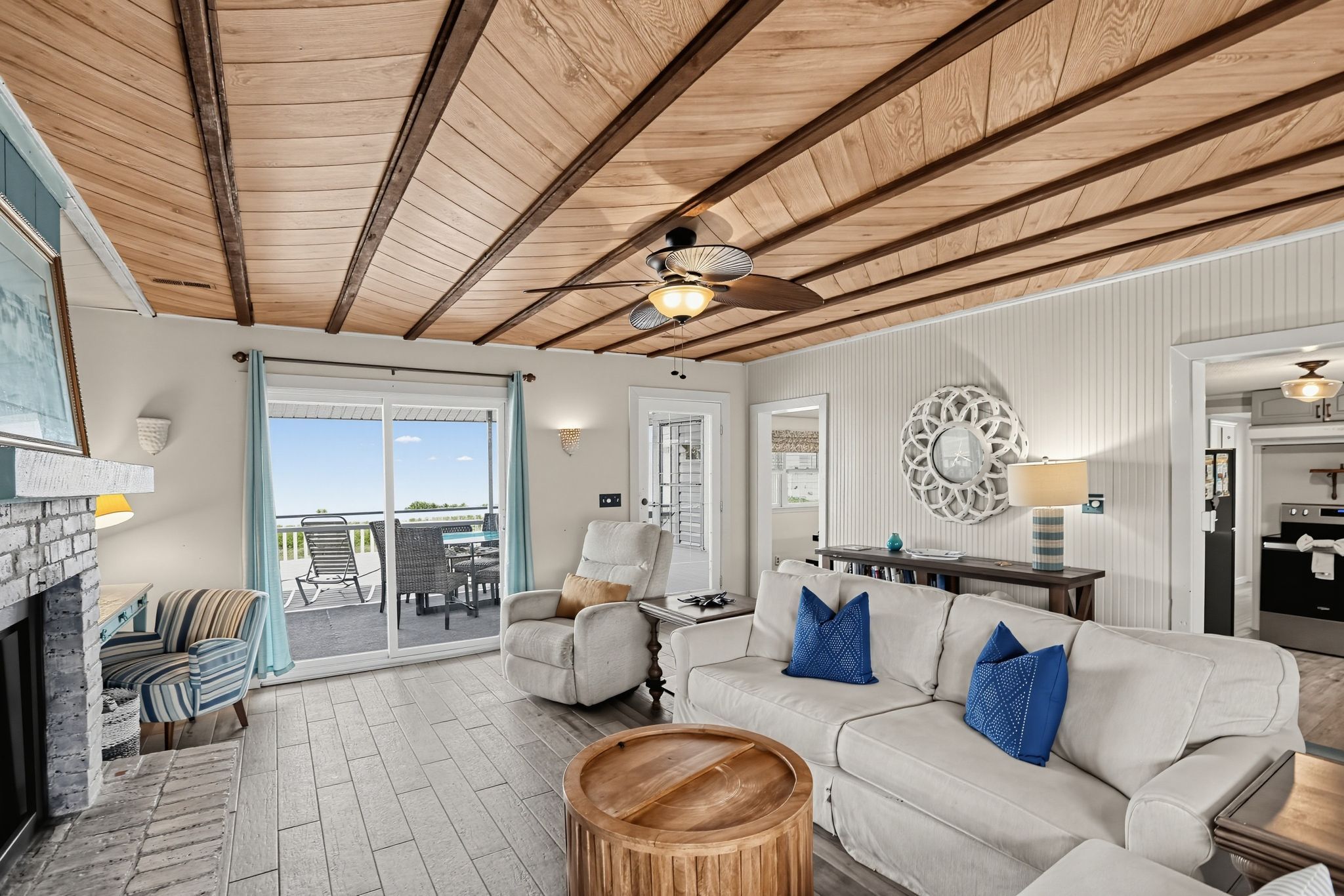 A spacious living area with a fireplace, a sofa with blue cushions, a wooden coffee table, and a ceiling fan.