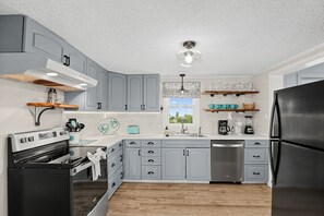 Eine moderne Küche mit grauen Schränken, Edelstahlgeräten und Holzböden.