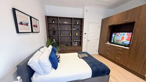 Un dormitorio moderno con una cama, un televisor, una estantería y una puerta.