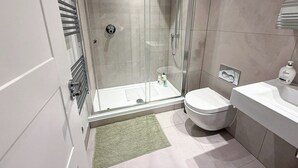 Un baño moderno con ducha envuelta en vidrio, inodoro y lavamanos.