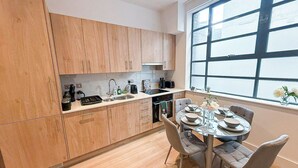 Una cocina moderna con armarios de madera, una mesa de comedor con sillas y un ventanal que proporciona luz natural.