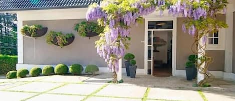 A house with a covered porch, potted plants, and a tiled patio.