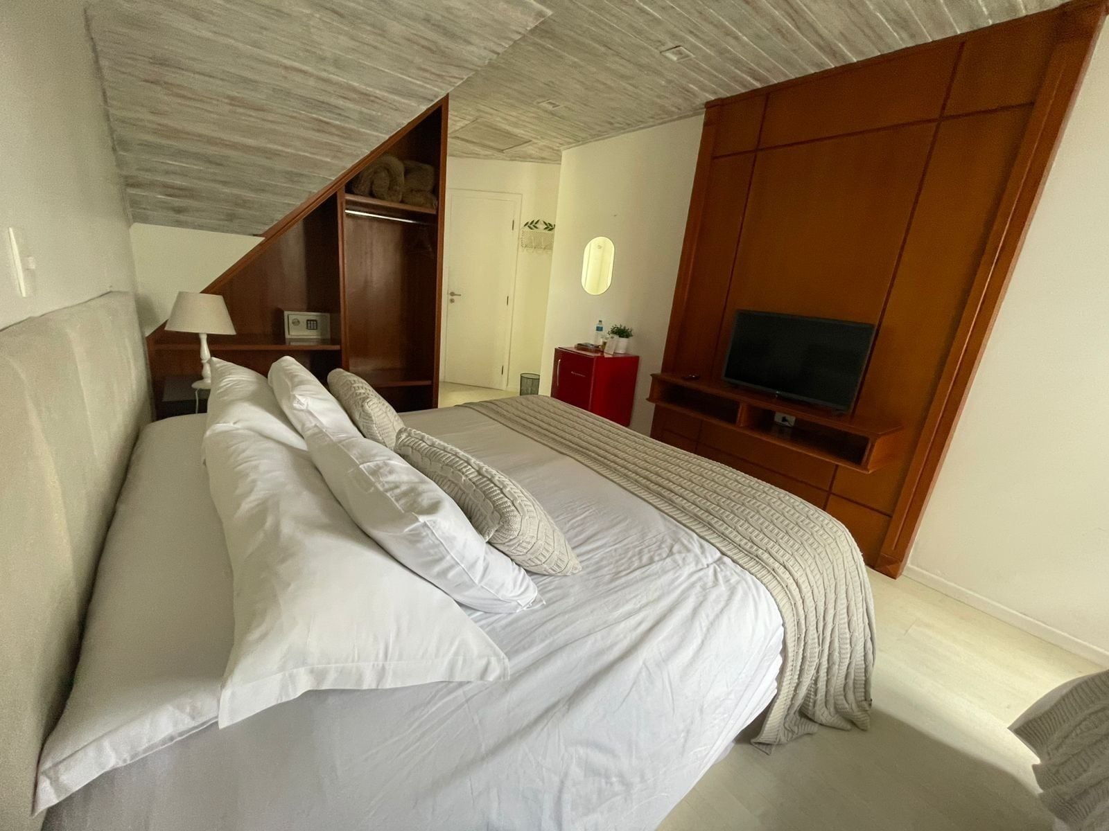 Ein Schlafzimmer mit einem großen Bett, einem Holzschrank, einem Fernseher und einem kleinen Schreibtisch mit Lampe.