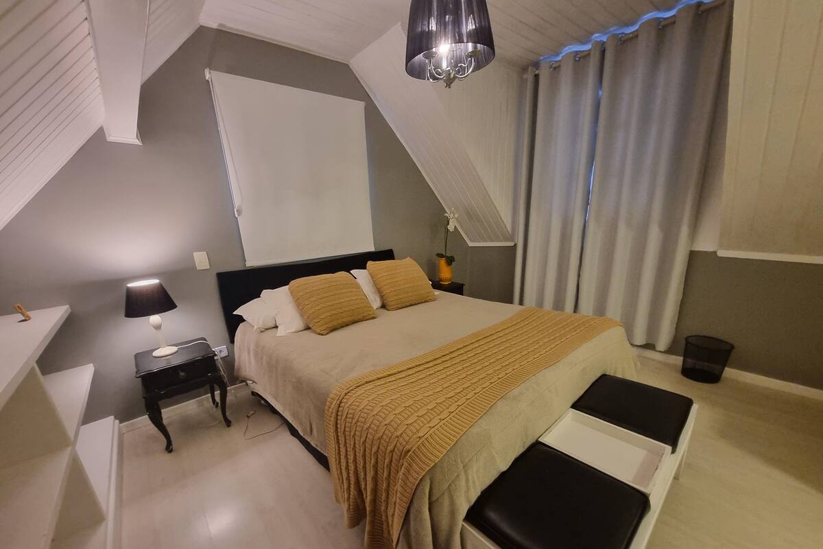 A bedroom with a bed, bedside table, lamp, and a hanging light fixture.