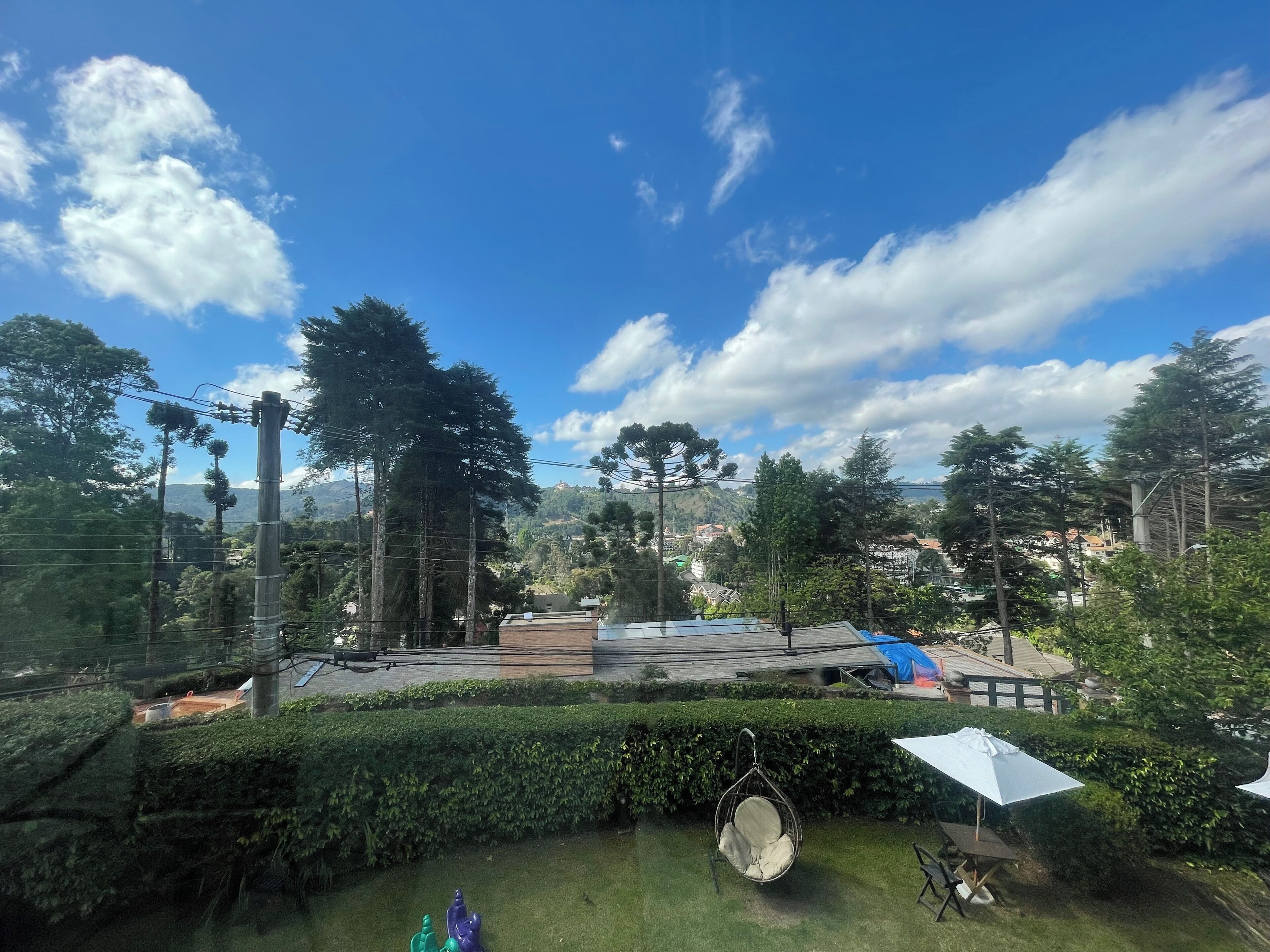 A residential area with a hanging chair, a white umbrella, and a view of a town with houses and trees.