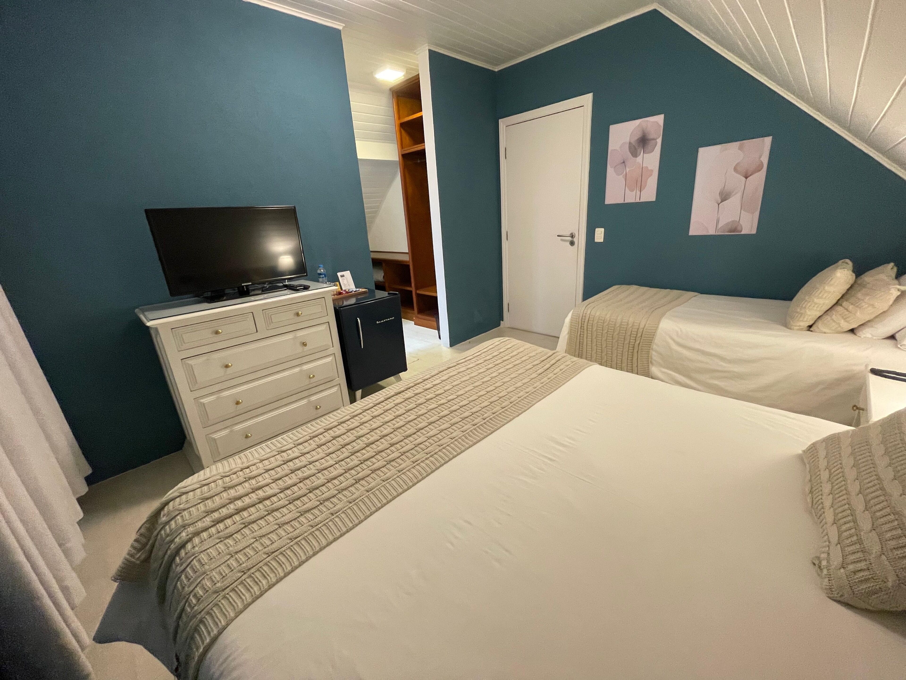 Un dormitorio con dos camas, un aparador, un televisor y un armario.