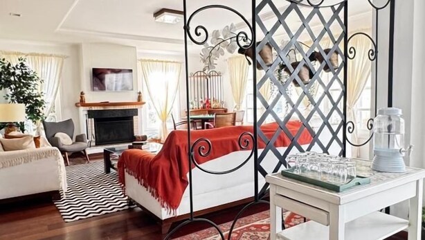A spacious living room with a large sectional sofa, a coffee table, and a decorative partition with a lattice design. - Pousada Vila de Charme Suítes (Campos do Jordão)