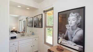 A bathroom with a large mirror, a sink, and a framed picture on the wall.