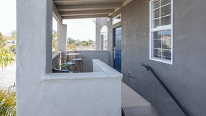 A covered outdoor area with a concrete bench, a small table with chairs, and a blue door. - After Dune Delight (Oceano)