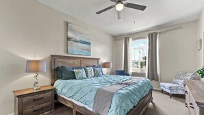 A bedroom with a bed, nightstands, a chair, and a ceiling fan. - Eye Sea (Oceano)