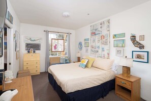 A bedroom with a bed, dresser, nightstand, and wall decorations. - Tide & Treasures (Oceano)